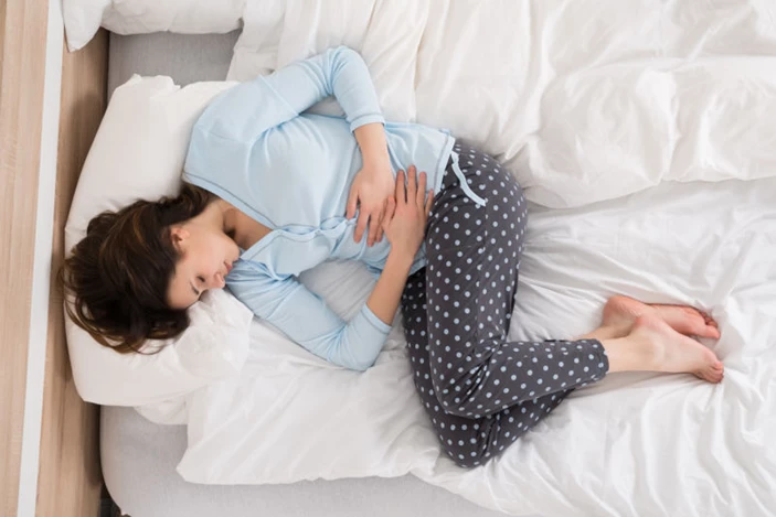 Mujer tumbada en la cama sujetando la barriga